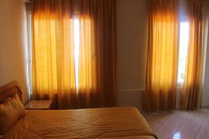 a bedroom with orange curtains and a bed and a window at Hotel Yassmina in Aourir