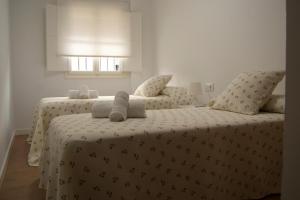 a bedroom with two beds with white sheets and pillows at Sánchez Home in Sanlúcar de Barrameda