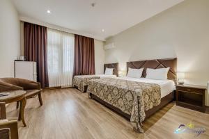 Habitación de hotel con 2 camas y sofá en Mirage Hotel, en Shekhvetili