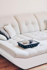 Hygge style apartment Nida في نيدا: صينية على أريكة بيضاء مع كوبين عليها
