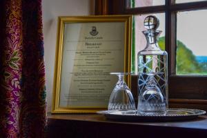 a glass bottle and a vase on a table next to a window at The Lady Maxwell Room at Buittle Castle in Dalbeattie