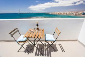 a table with a bottle of wine and two chairs at Arinaga Colors, tu casa en la playa in Arinaga