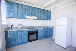 a kitchen with blue cabinets and a white refrigerator at Arinaga Colors, tu casa en la playa in Arinaga