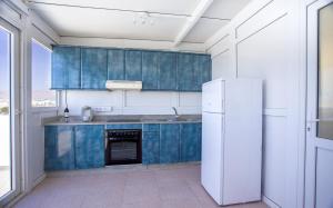 a kitchen with blue cabinets and a white refrigerator at Arinaga Colors, tu casa en la playa in Arinaga