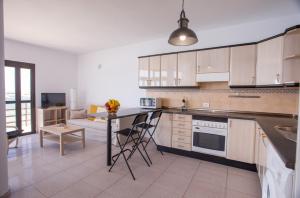 a kitchen with white cabinets and a table with chairs at Arinaga Colors, tu casa en la playa in Arinaga