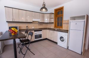 a kitchen with white appliances and a table with a bowl of fruit at Arinaga Colors, tu casa en la playa in Arinaga
