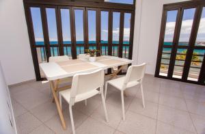 a white table and chairs in a room with windows at Arinaga Colors, tu casa en la playa in Arinaga
