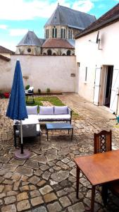 a patio with couches and a table and an umbrella at Chambre privée dans maison centre-ville Sens Petit-déjeuner compris in Sens