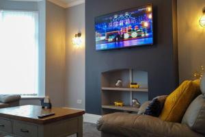 a living room with a couch and a tv on the wall at Westcliffe House in Blackpool