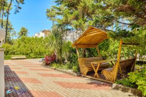 a wooden gazebo with benches in a park at Mirage Hotel in Shekvetili