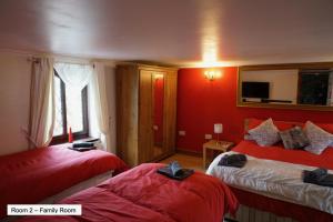 2 Betten in einem Zimmer mit roten Wänden in der Unterkunft Pentre Riding Stables in Abercraf