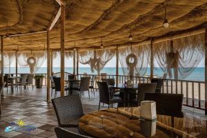 un restaurante con mesas y sillas y vistas al océano en Mirage Hotel en Shekhvetili