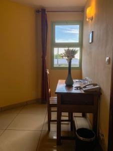 a room with a table with a vase with flowers on it at Java Hotel in Toamasina