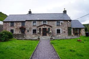 an old stone house with a grass yard at Pentre Riding Stables in Abercraf