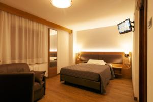 una camera d'albergo con letto e sedia di Albergo Antelao a San Vito di Cadore