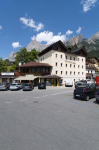 a large white building with cars parked in a parking lot at Albergo Antelao in San Vito di Cadore