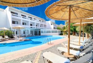 a hotel with a swimming pool with chairs and umbrellas at Elounda Krini Hotel in Elounda