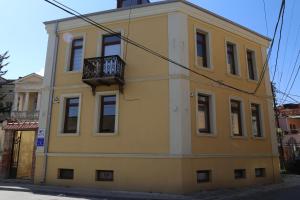 a yellow building with a balcony on a street at Nestor Apartments in Bitola