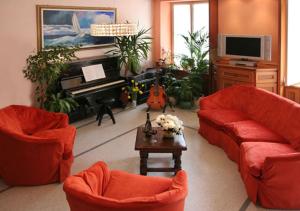 a living room with two red couches and a piano at Hotel Badano sul Mare in Alassio