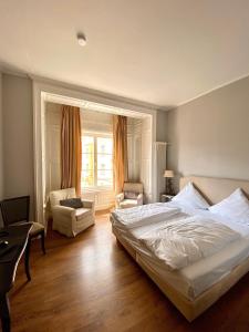 a bedroom with a bed and a chair and a window at Das Nikolai Hotel in Munich