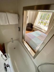 a bathroom with a tub with a window and a bed at Das Nikolai Hotel in Munich +79 photos