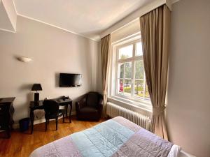 a bedroom with a bed and a window and a desk at Das Nikolai Hotel in Munich
