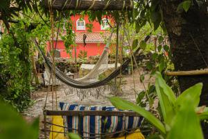 a hammock in a garden with a red building at MangaMel Hostel in Lençóis