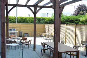 a patio with tables and chairs and a wooden pergola at Staybridge Suites London Heathrow - Bath Road, an IHG Aparthotel in Hillingdon