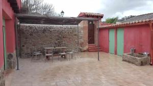 a patio with a table and chairs next to a building at Casa Rural Rojo del Tietar in La Iglesuela