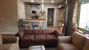 a living room with a brown couch and a kitchen at Casa Rural Rojo del Tietar in La Iglesuela