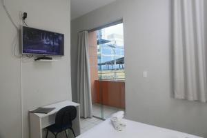 een kamer met een tv en een bureau met een stoel bij Campos Gerais Hotel in Belo Horizonte