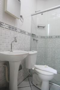 a white bathroom with a toilet and a sink at Campos Gerais Hotel in Belo Horizonte