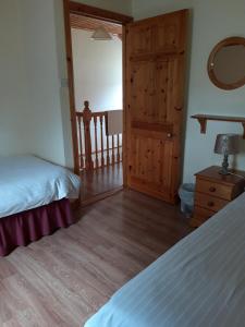 1 dormitorio con 2 camas y puerta de madera en Riverbank Cottages en Scarriff