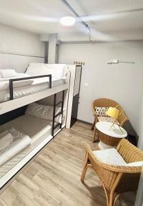 a room with a bunk bed and chairs and a table at Quartier Bilbao Hostel in Bilbao