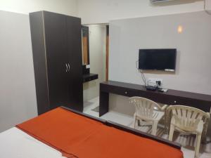 sala de estar con TV, mesa y sillas en Hotel Sarada Nivas, en Chennai