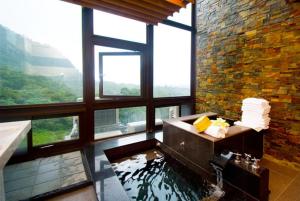 a bathroom with a bath tub with a large window at Jiaoxi Guanjinglou Hot Spring Club in Jiaoxi