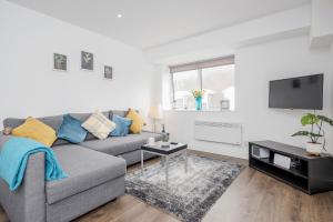 a living room with a gray couch and a flat screen tv at Watford Central Serviced Apartments - F5 in Watford
