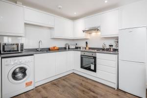 a kitchen with white cabinets and a washer and dryer at Watford Central Serviced Apartments - F5 in Watford
