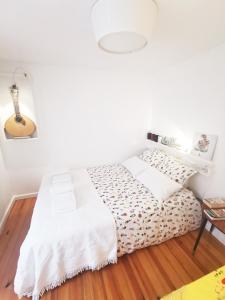 a white bed in a room with a wooden floor at Canto do Fado Home in Lisbon