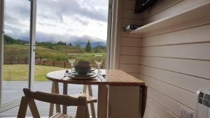 a small table with two glasses of wine on a porch at Toradh Cabin in Spean Bridge