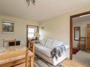a living room with a white couch and a table at Grouse Cottage in Newtonmore