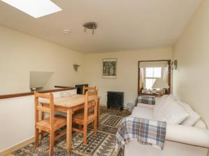 een woonkamer met een tafel en een bank bij Grouse Cottage in Newtonmore