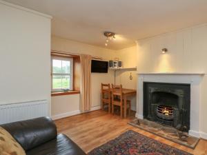 a living room with a fireplace and a table at Osprey Cottage in Newtonmore