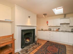 a kitchen with a fireplace in the middle of a room at Osprey Cottage in Newtonmore