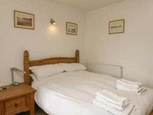 a bedroom with a white bed with towels on it at Osprey Cottage in Newtonmore