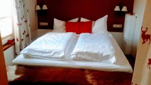 a large bed with white sheets and red pillows at Superior Apartment Recktenwald in Bad Gastein