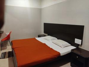 a bedroom with a bed with an orange blanket at Hotel Sarada Nivas in Chennai