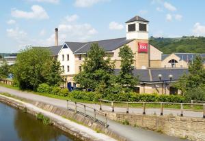 een gebouw met een klokkentoren naast een rivier bij ibis Bradford Shipley in Bradford