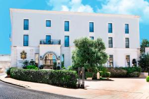 un edificio bianco con un cancello davanti di OSTUNI PALACE - Hotel Bistrot & SPA a Ostuni