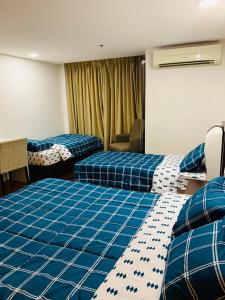 a hotel room with two beds with blue sheets at Staycity Apartments - Kota Bharu City Point in Kota Bharu